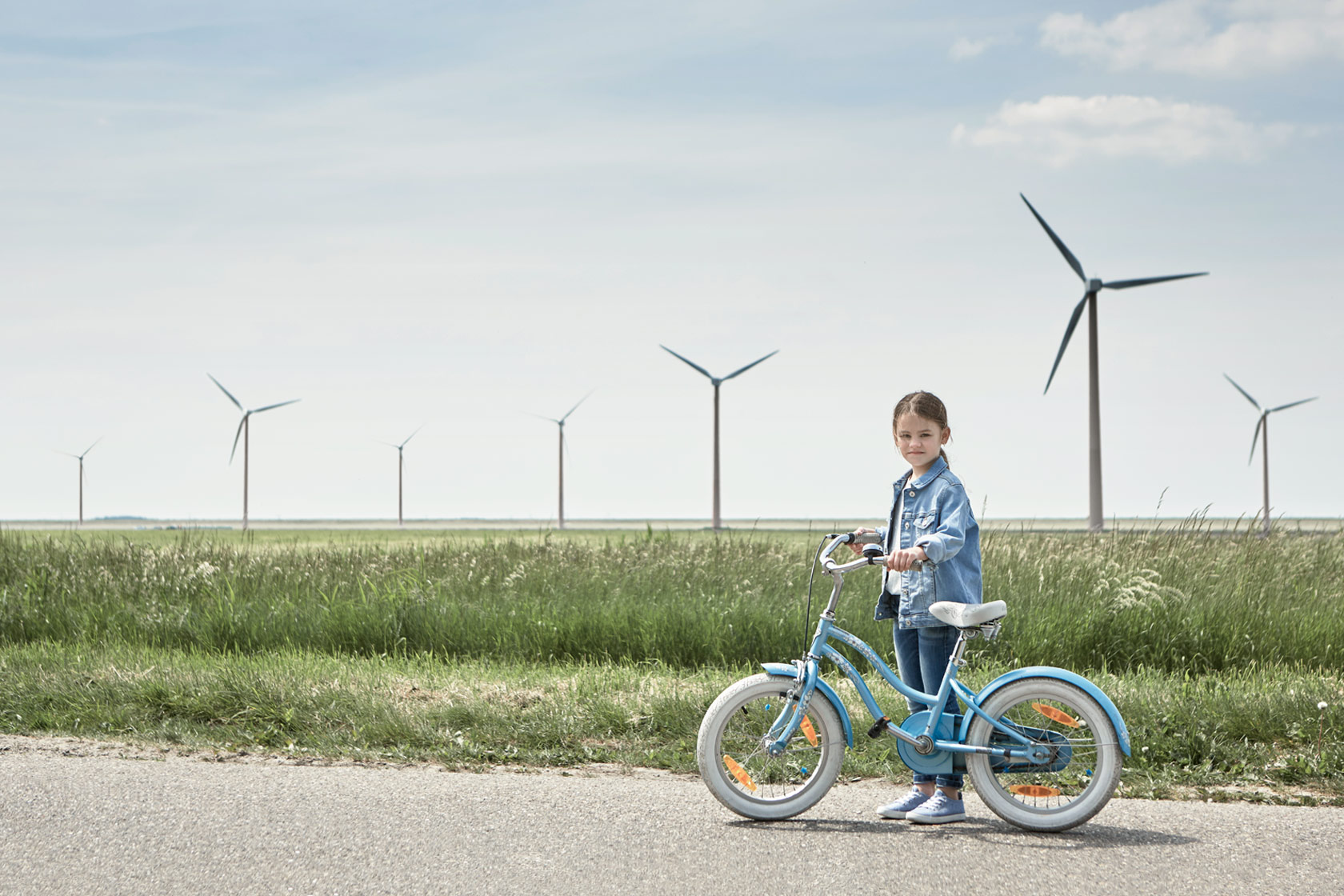 Girl with a bike in front of a wind farm