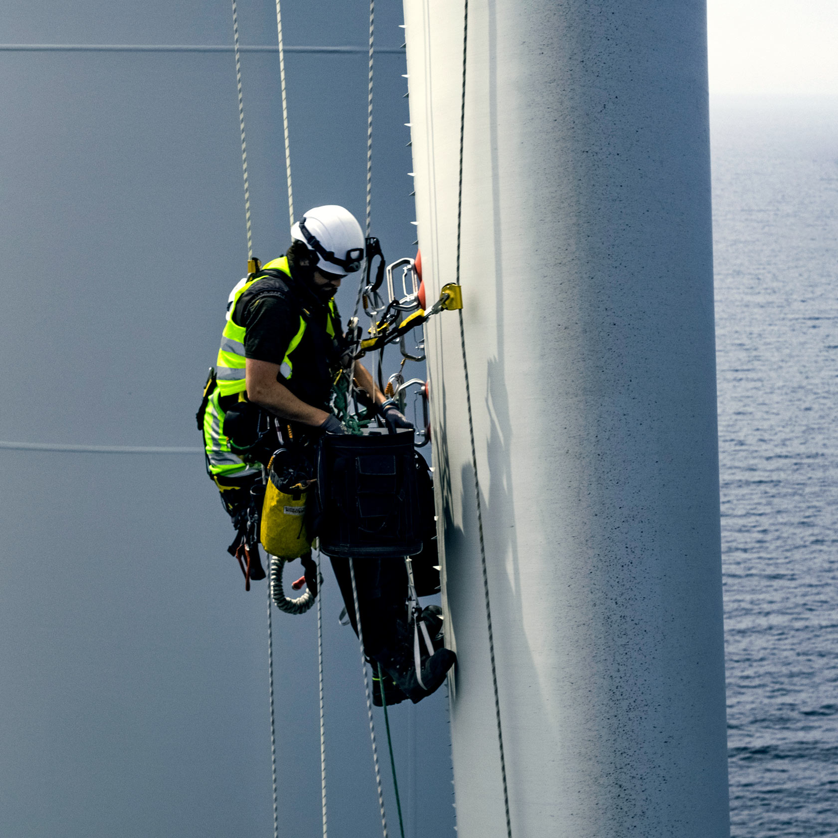 Man i skyddsutrustning på rotorblad i ett havsbaserat vindkraftverk