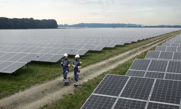 Zwei Mitarbeiter in Schutzkleidung in einem Solarpark